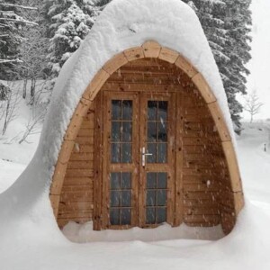 Bungalow POD in legno ricoperto di neve durante l’inverno