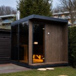 Sauna da esterno moderna in legno con ampia vetrata panoramica e stufa a legna