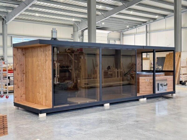 Sauna da esterno in legno con stufa a legna e grande vetrata frontale