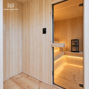 Zona relax della sauna FRAME con porta in vetro e stufa visibile all’interno